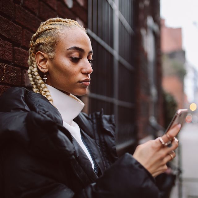 vintage toned portrait of a young blond latinx new yorker woman, texting on her smartphone on the west village, in lower manhattan area she is wearing casual but stylish clothes, waiting for her friend to arrive