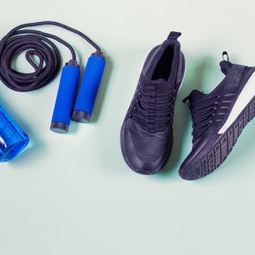 sport items jumping rope, sport shoes, blue bottle with water items arranged on light green background photo with copy blank space