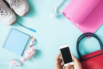 Cropped Hands Of Woman Holding Mobile Phone By Personal Accessories Over Blue Background