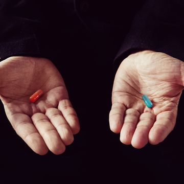 red tablet in the left palm blue pill in his right hand