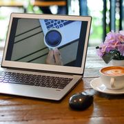 coffee cup by laptop on table