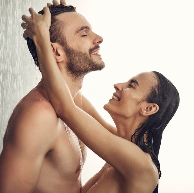 loving pair having shower while standing under water in the bath room and smiling