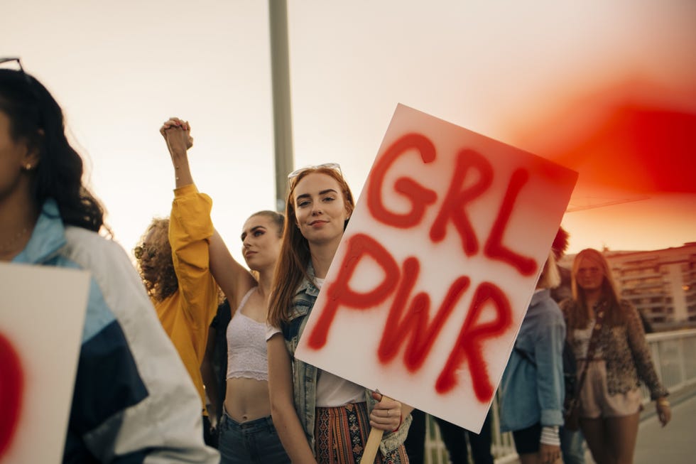 participants at a rally holding a sign that reads grl pwr