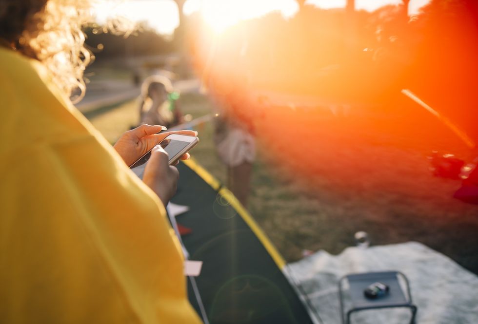 cropped image of woman using mobile phone while standing by tent on sunny day