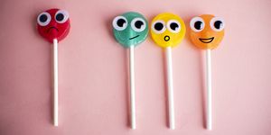 green lollipop with cartoon eyes on pink colored background, bullying concept