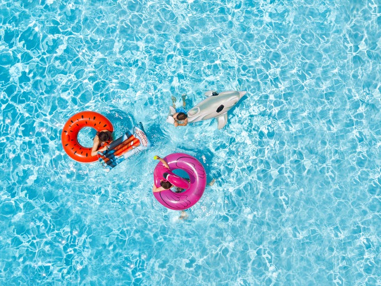 Three childred on inflatable floats in swimming pool