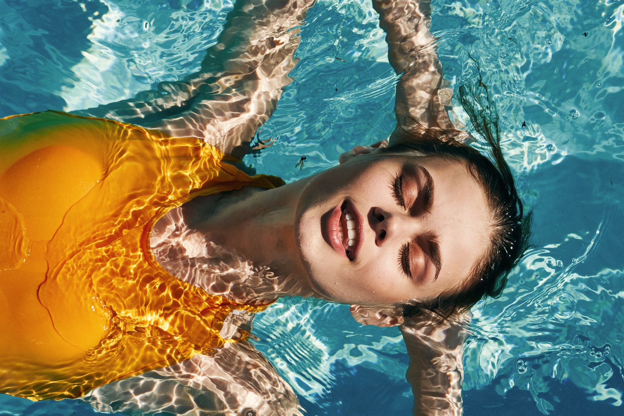 beautiful girl in a yellow swimsuit swims in the pool