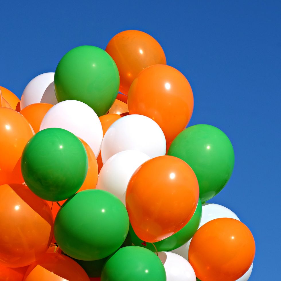 green orange and white balloons floating in a blue sky