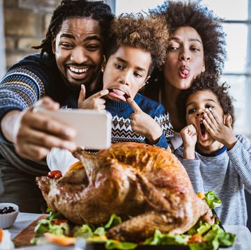 happy african american family having fun while making faces and taking a selfie with cell phone during thanksgiving dinner
