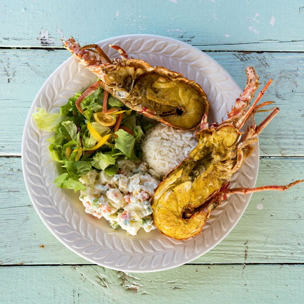 dish with fresh lobster with rice and vegetables on wood table background, caribbean