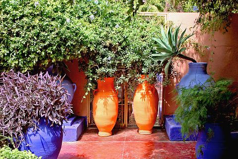 mediterranean garden with terracotta tiled floor and blue and orange pots with plants