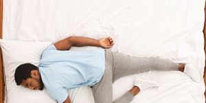 comfortable pose for sleep black millennial guy sleeping, lying on stomach in bed, top view