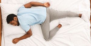 comfortable pose for sleep black millennial guy sleeping, lying on stomach in bed, top view