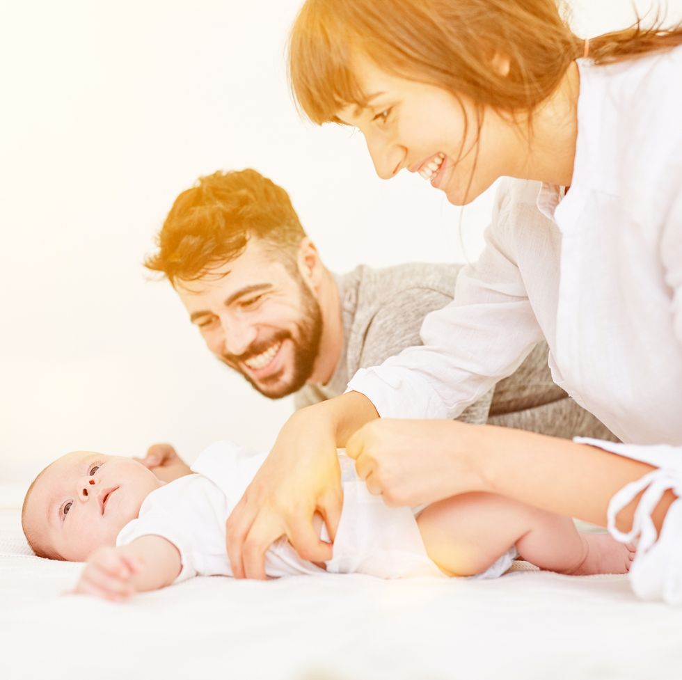 Happy Parents Playing With Son On Bed At Home