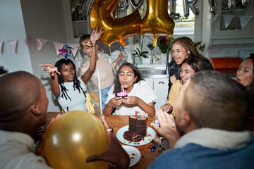 excited friends enjoying with woman blowing birthday candles during party at home