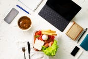 top view of the office work place with computer or laptop pen and phone, nutritious lunch during the works