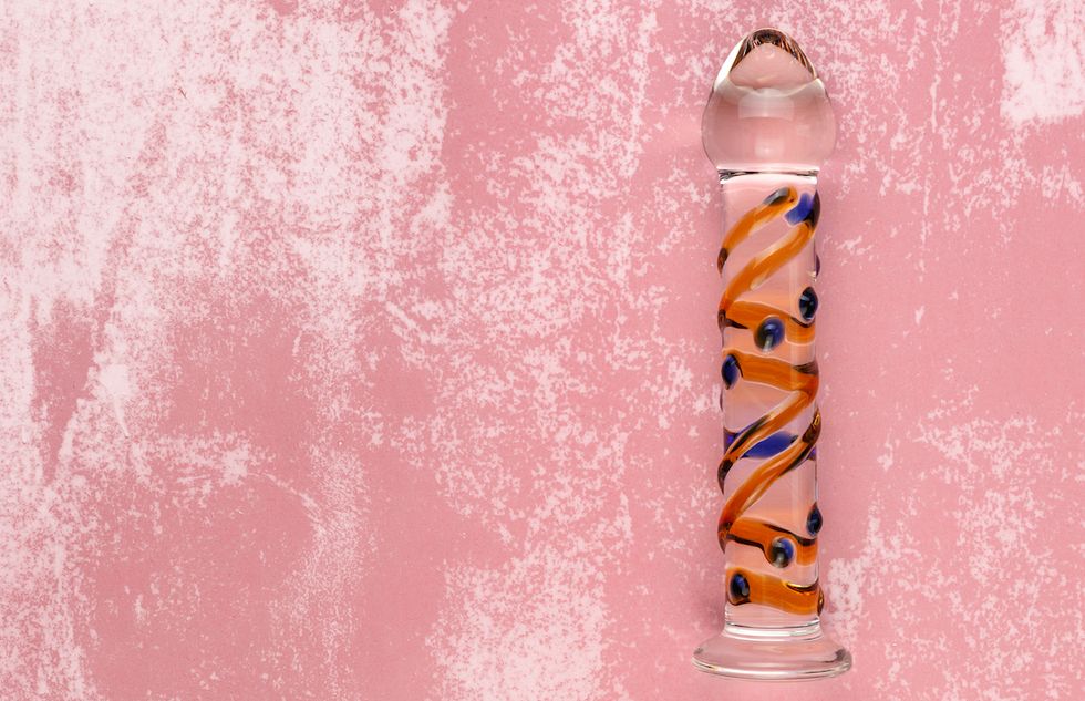 beautiful evenly lit glass dildo on a dirty pink background with copy space
