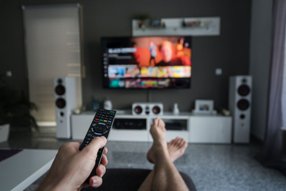 a young man is browsing through television channels with a remote control