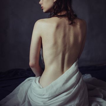a woman with her back turned to the camera, no shirt on