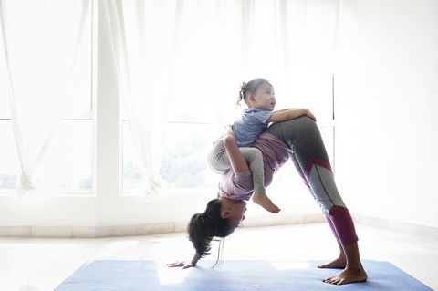 Woman doing yoga with daughter on her back