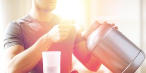 sport, fitness, healthy lifestyle and people concept   close up of man with jar and bottle preparing protein shake