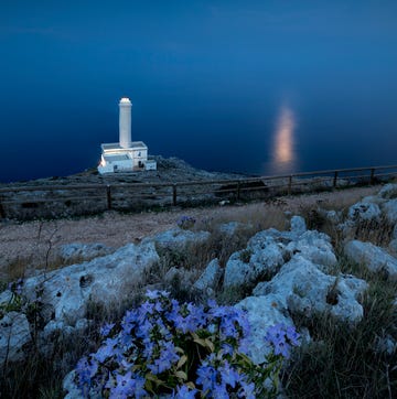 blue dusk and moon reflected in the sea frames the lighthouse at punta palascia, otranto, province of lecce, apulia, italy