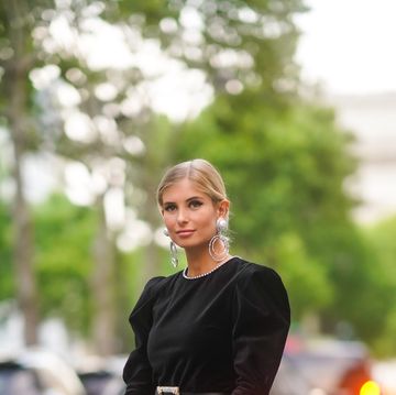 paris, france   june 30 xenia adonts wears large earrings, rings,  a rhinestone trimmed collar black mini dress, a black belt with a glittering rhinestone buckle, a grey minaudiere, black ankle strap sandals with black tulle bow , outside amfar dinner, during paris fashion week   haute couture fallwinter 20192020, on june 30, 2019 in paris, france photo by edward berthelotgetty images