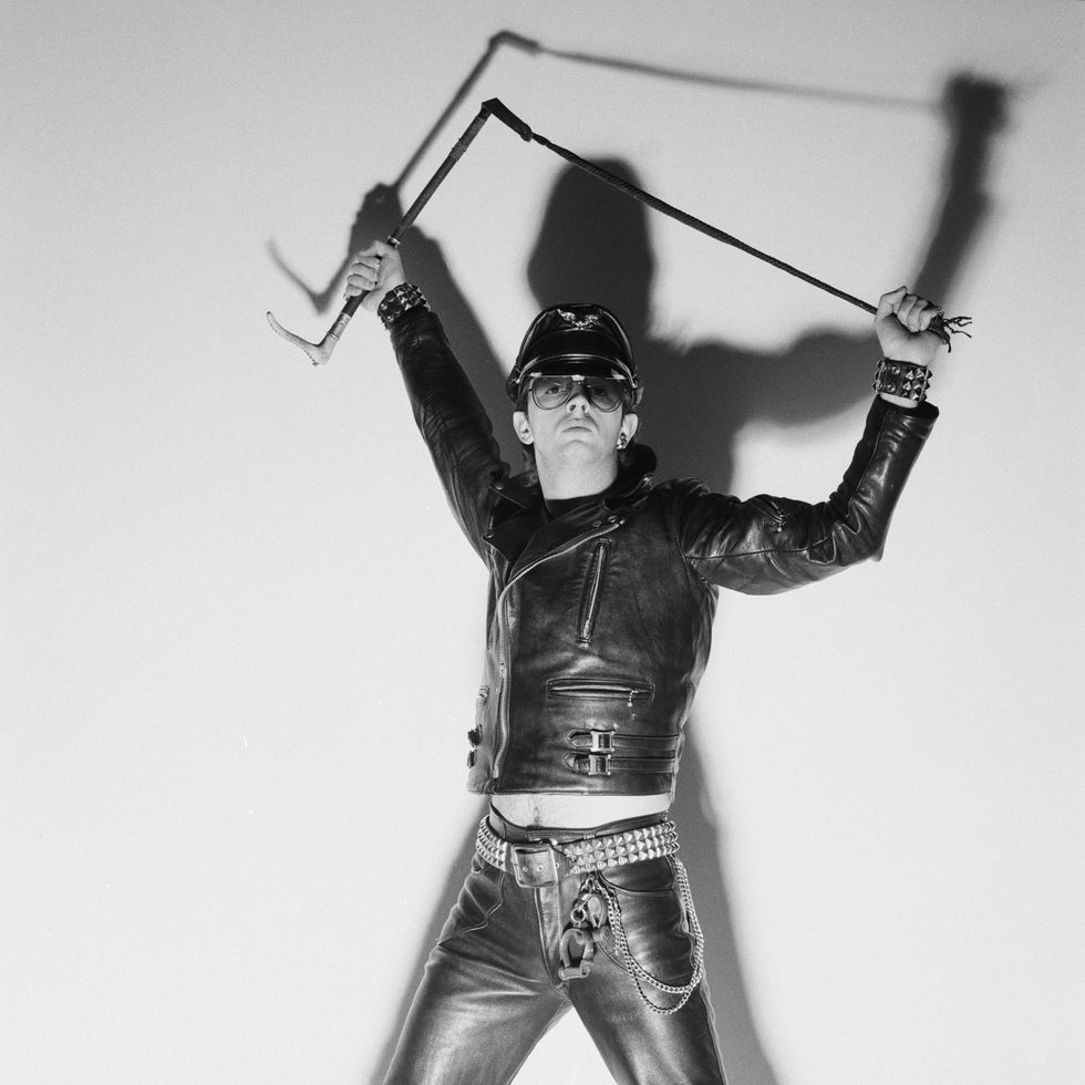 rob halford, singer with british heavy metal band judas priest, poses wearing black leather clothing, and holding a whip above his head, his shadow projected against the white background, in a studio portrait, circa 1978 photo by fin costelloredfernsgetty images