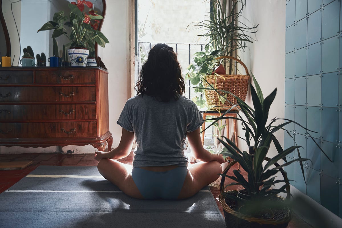 Rear View Of Woman Meditating While Sitting At Home