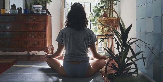 Rear View Of Woman Meditating While Sitting At Home