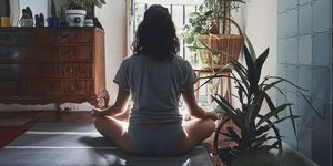 Rear View Of Woman Meditating While Sitting At Home