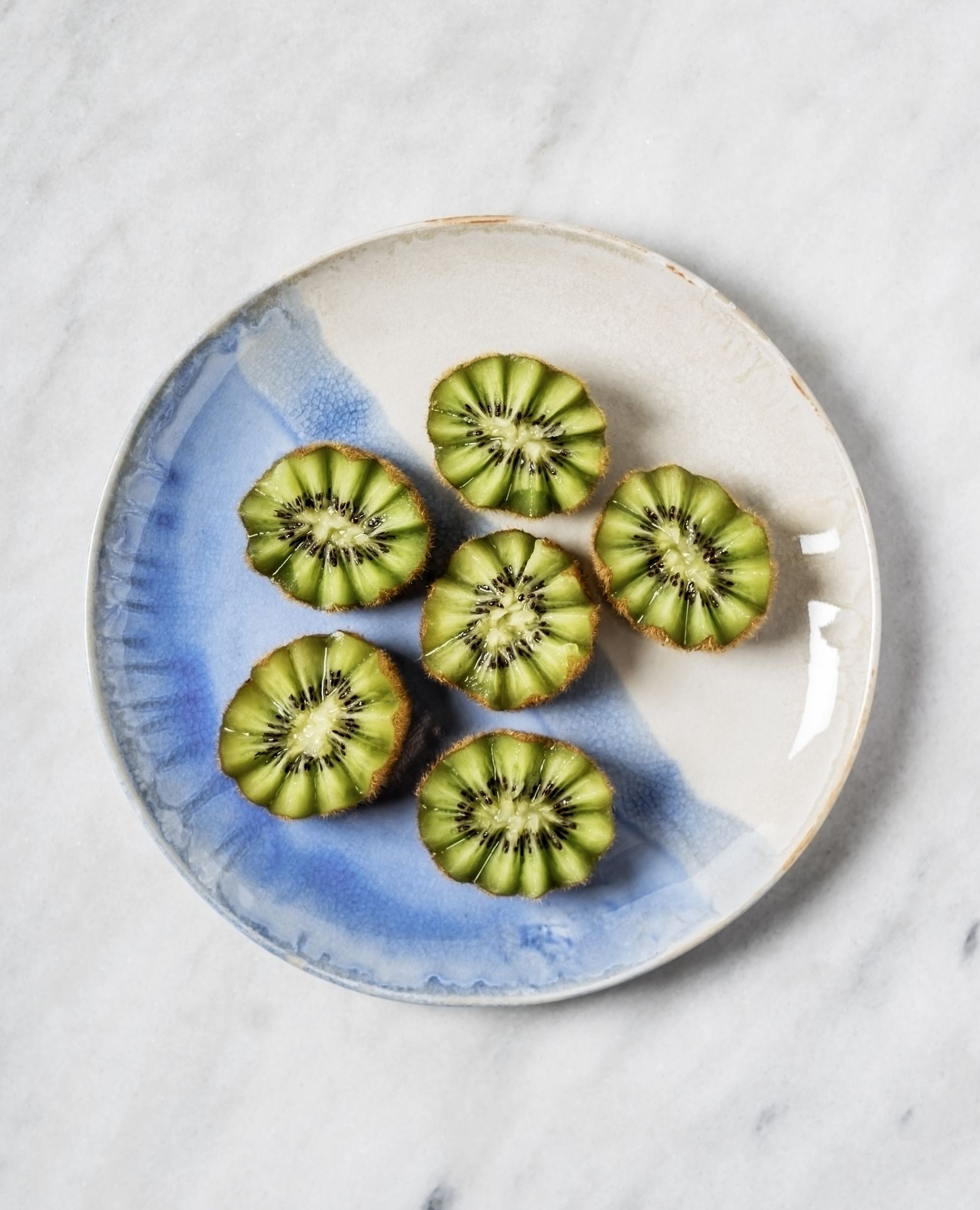 Slices of kiwi on a plate on white background
