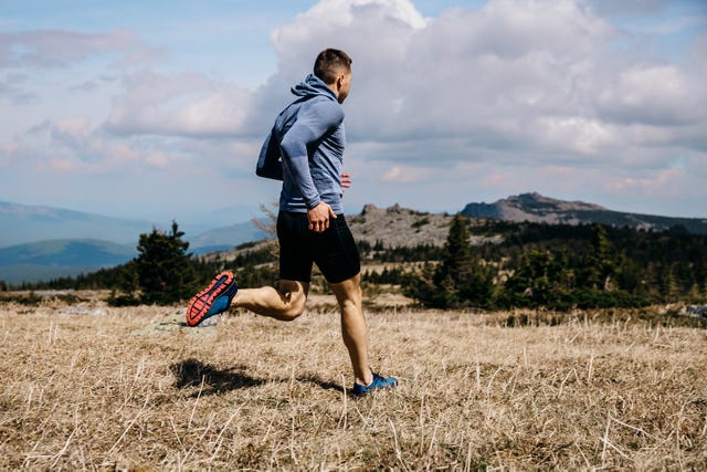 man runner running mountain marathon trail on yellow grass