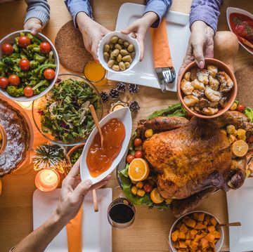 high angle view of unrecognizable people passing side dishes during thanksgiving dinner at dining table