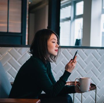 mujer mirando el móvil con un cafÉ