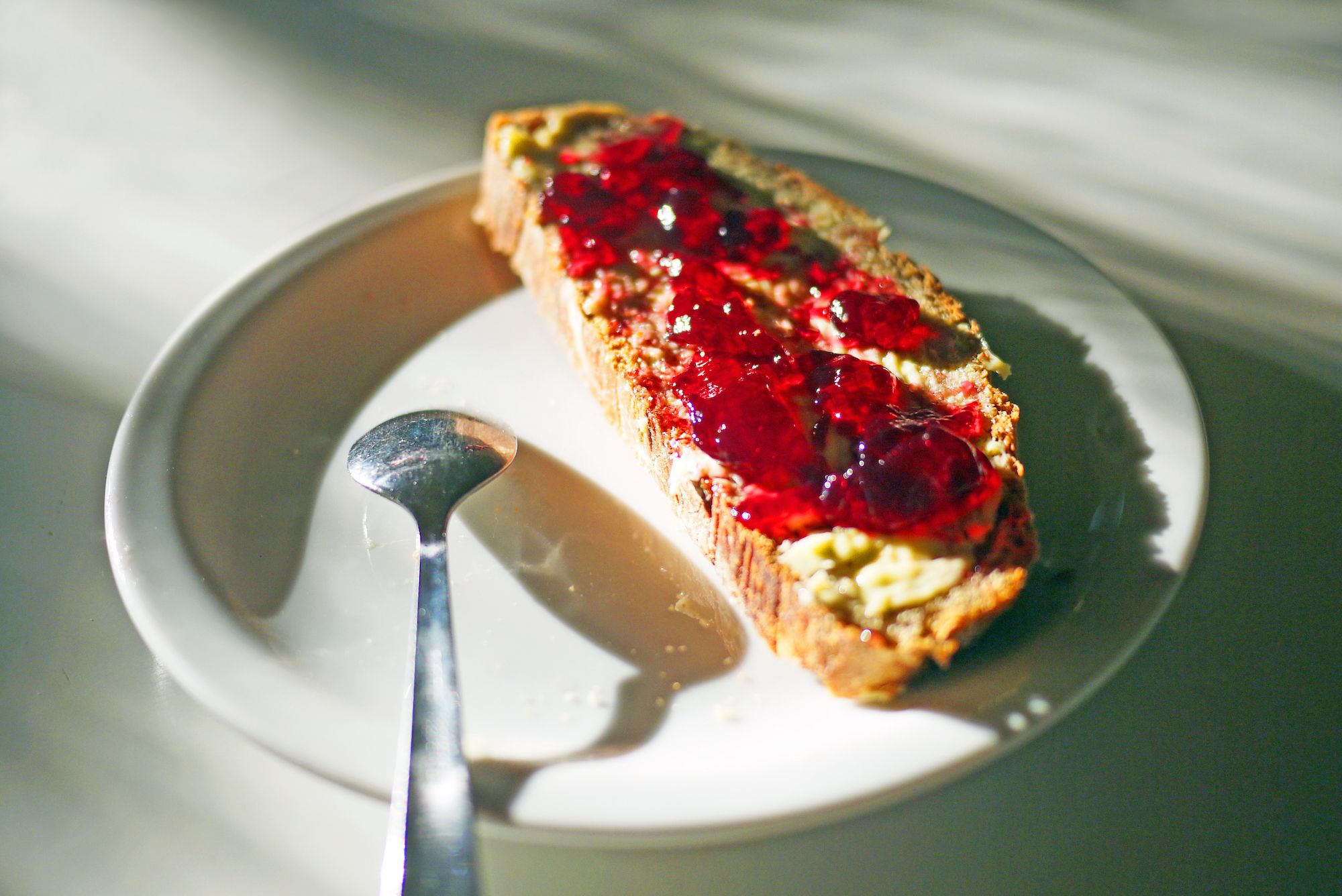 A slice of bread with butter and red jam