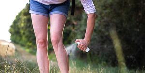 Woman tourist spraying insect repellent against tick and mosquito in nature.