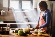 young black man chopping vegetables while preparing food in the kitchen copy space