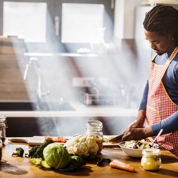 young black man chopping vegetables while preparing food in the kitchen copy space
