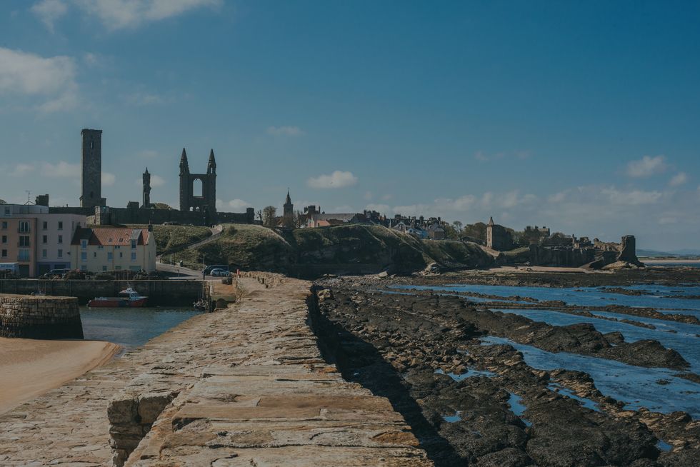 view towards the ruins of st andrews cathedral and castle seen from the pier in st andrews, fife, scotland the north sea is at low tide