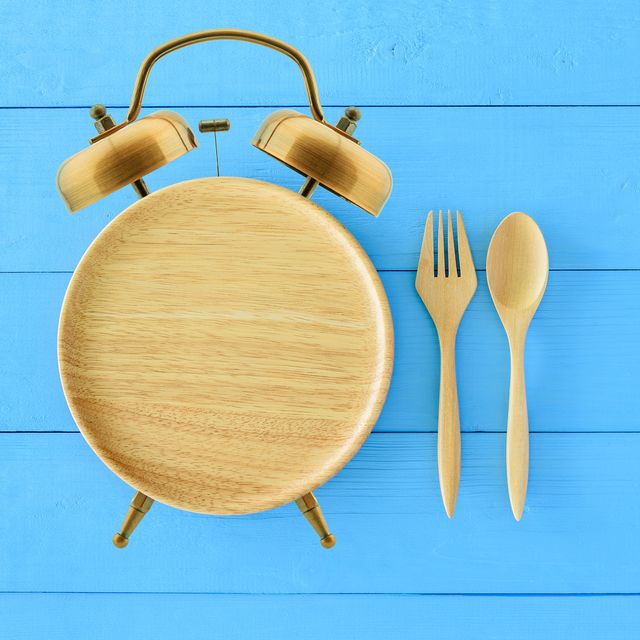 Intermittent fasting, diet and weight loss concept : Clock shaped wood dish, spoon and fork. Eco-friendly plate / kitchen utensil as alarm clock with ringing bell, depict alert or reminder time to eat