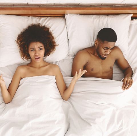 sex problem disappointed black unsatisfied woman lying in bed, sad man looking under blanket, top view