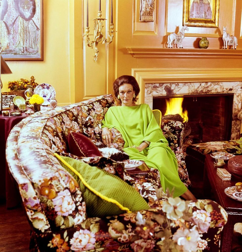 vogue, february 01, 1976   socialite pat buckley nee patricia alden austin taylor seated with her cocker spaniel dog in the living room of her stamford, connecticut, home, which was designed by tom fleming of irvine and fleming the walls are a vivid orange, and she wears a bright green caftan while sitting on a dark, floral patterned sofa that dominates the room the room also includes a marble fireplace christian icons horse statuettes gold wall mounted candelabra antique plates  ernst beadleconde nast via getty images