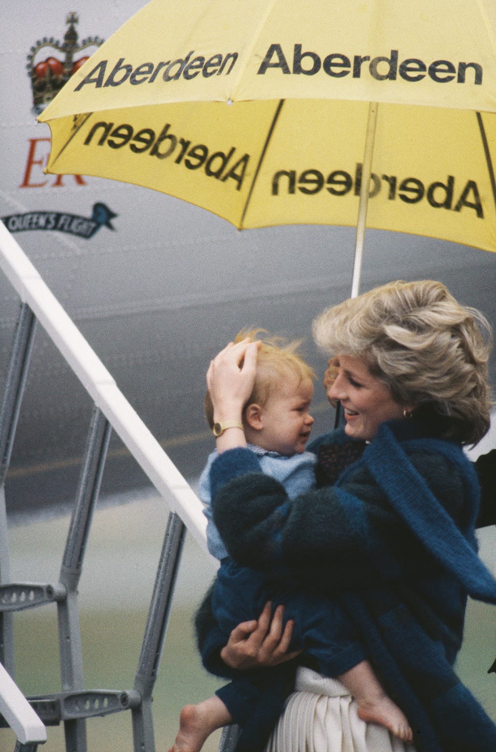 diana, princess of wales shelters her son prince harry from the rain