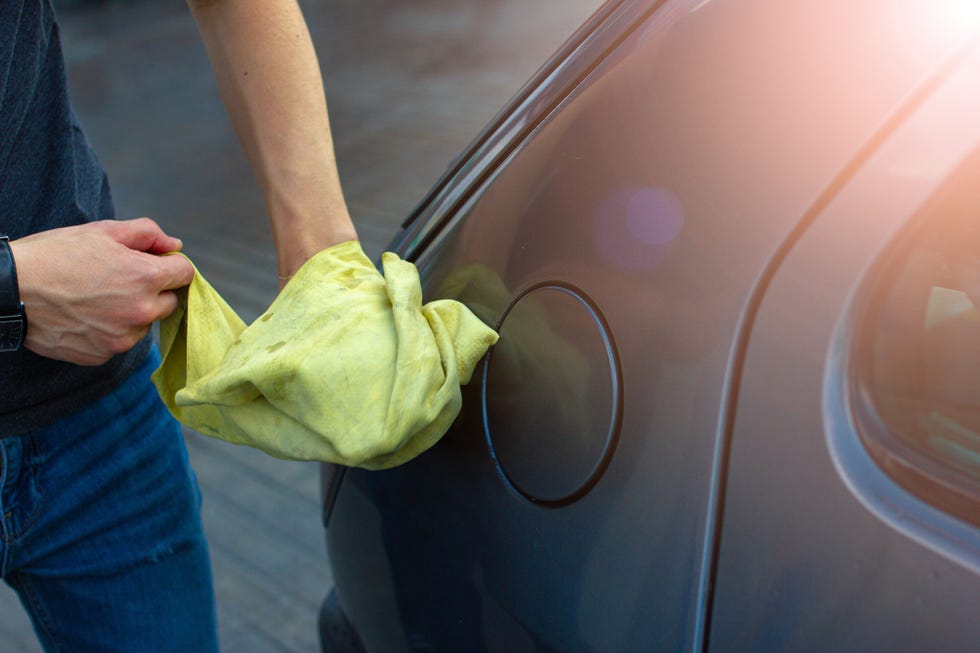 man polishes and wipes the car with a rag after washing.
