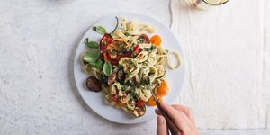Eating Fettucine with roasted colorful vegetables and parsley  pesto