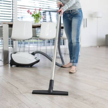 canister vs upright vacuum which should you choose image of a woman vacuuming a wood floor