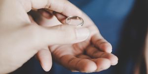 A young couple's hands holding a wedding ring, a concept of divorce