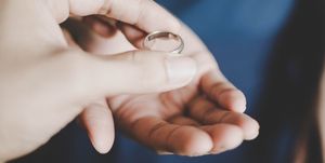 A young couple's hands holding a wedding ring, a concept of divorce