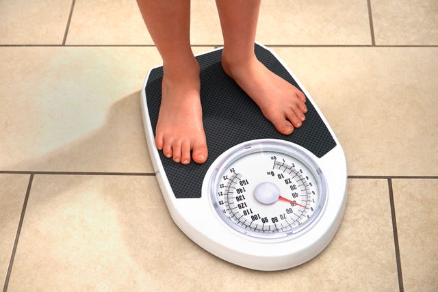 8 year old boy weighing himself on bathroom scales at home